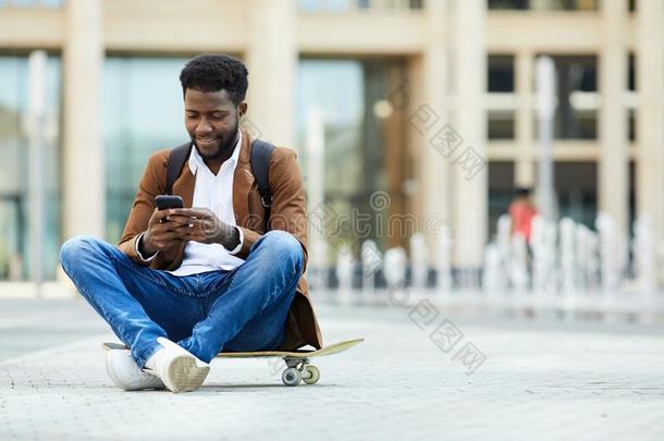 年幼的非洲的-美国人男人发短信采用城市正方形