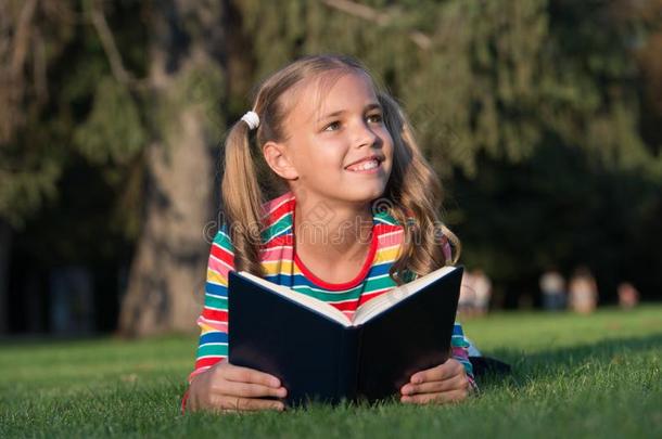 小的小孩阅读书在户外.女学生阅读故事wickets三柱门