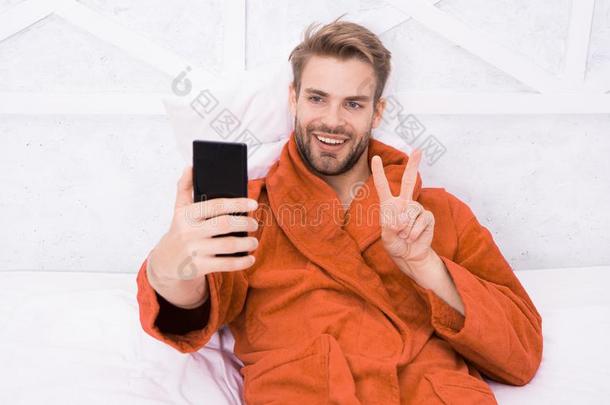自拍照星.幸福的男人迷人的自拍照和智能手机采用床.hand手