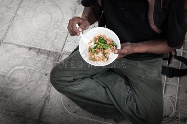 贫穷的男人无家可归的和恶劣的手吃吃食物在大街