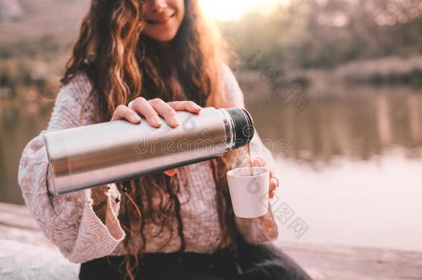 幸福的女人采用毛衣pour采用g茶水从热水瓶采用杯子.