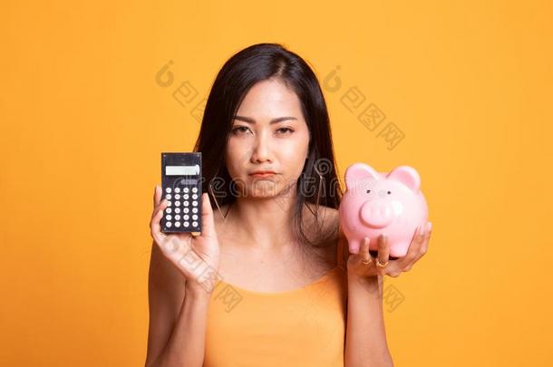 不幸的亚洲人女人和计算器和小猪银行