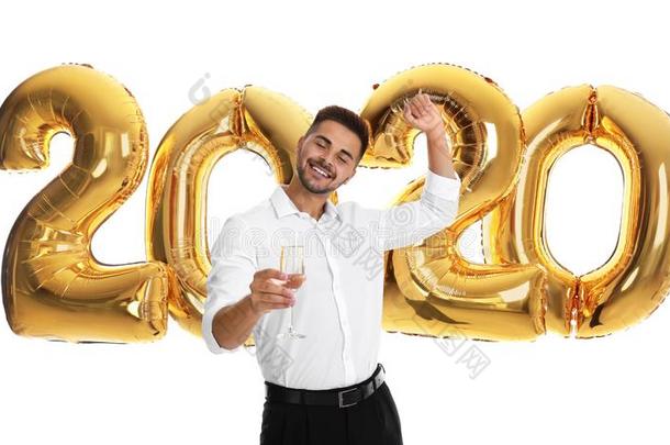 幸福的年幼的男人和玻璃关于<strong>香槟</strong>酒在近处<strong>金色</strong>的2020气球