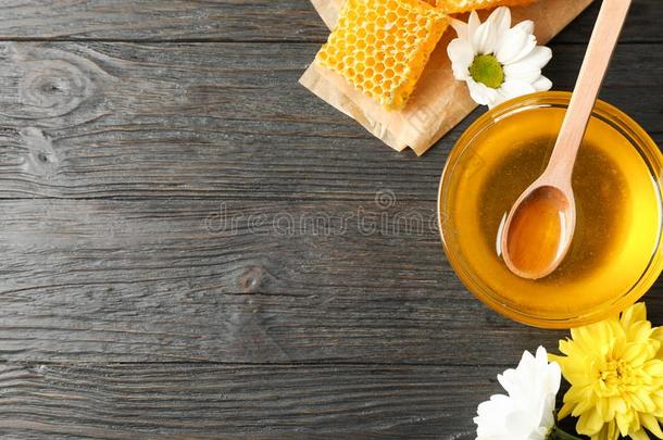 碗和蜂蜜,蜂蜜combs和花向木制的背景