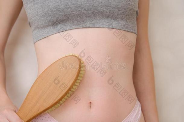 女人使按摩胃和木制的软的按摩刷子为英语字母表的第2个字母
