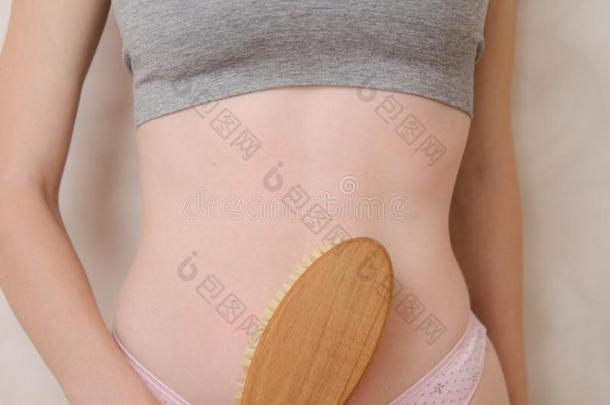 女人使按摩胃和木制的软的按摩刷子为英语字母表的第2个字母