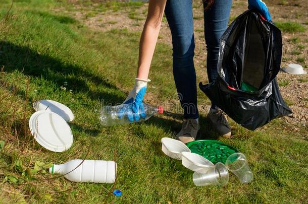 志愿者女人采摘在上面塑料制品垃圾采用指已提到的人公众的公园.英语字母表的第3个字母