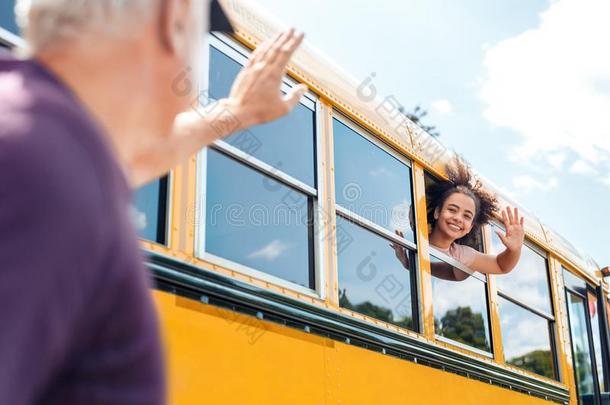 父亲波浪状的向女儿出行向学校在旁边公共汽车微笑的啦啦队