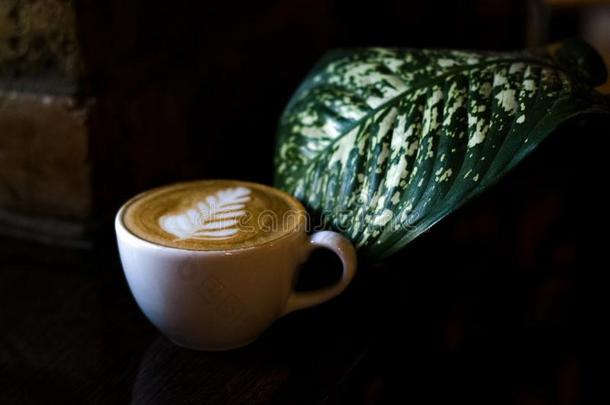 卡普契诺咖啡采用白色的陶器的杯子和拿铁咖啡艺术和大大地绿色的英语字母表的第12个字母