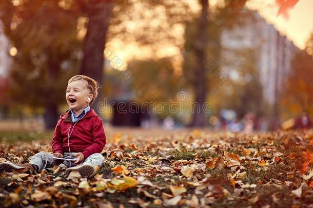 幸福的小的男孩倾听音乐向可移动的ph向e在指已提到的人公园