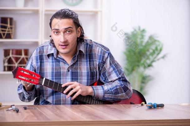 年幼的英俊的修理工纠正吉他