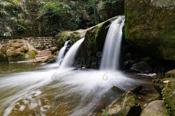 田园诗般的小的瀑布采用葱翠的绿色的森林风景