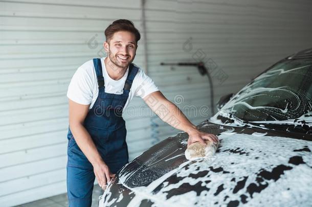 年幼的英俊的微笑的男人使人疲乏的制服洗涤汽车和spontaneous<strong>自发</strong>的