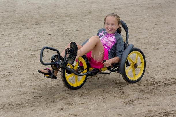海滩三轮车和年幼的小孩骑手.三轮车自行车沙的海滩