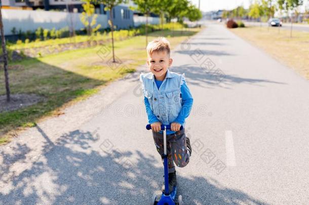 幸福的小的男孩骑马小型摩托车采用城市