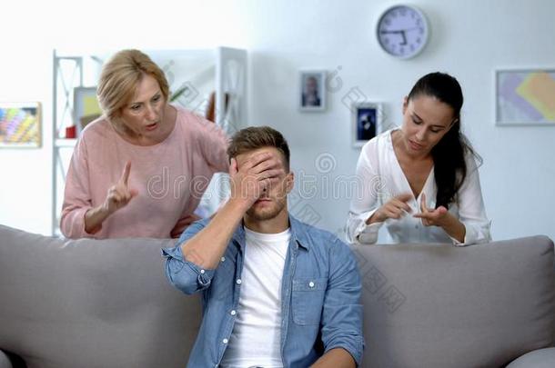 疲倦的男人一次向沙发,持久的向妻子和母亲分析