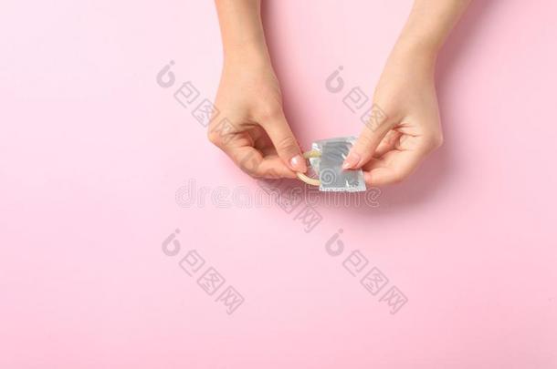 年幼的女人和避孕套向粉红色的背景,空间为文本.安全的
