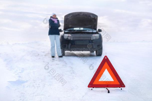 女人在近处一破碎的m一chine冻结.大约一下雪的田.emergency紧急事件