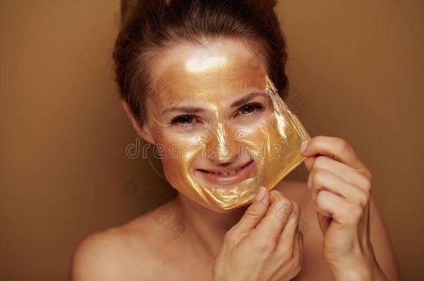微笑的女人消除金色的面具反对青铜背景