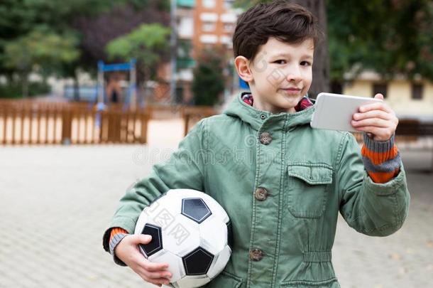 男孩佃户租种的土地足球球和智能手机在户外