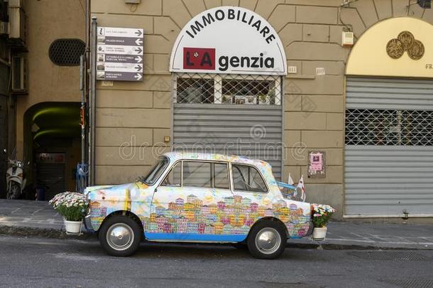 古老的白色的汽车和上油漆关于热那亚,旗关于热那亚,和英语字母表的第6个字母