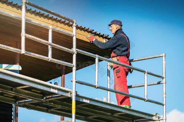 男人向搭脚手架的材料安装新的木制的木板向房屋屋顶eac每
