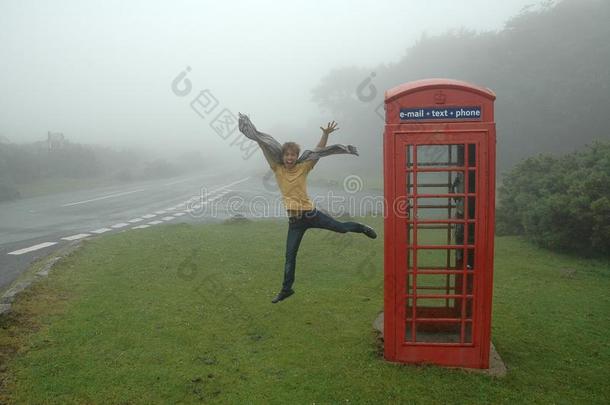 幸福的人用于跳跃的在近处红色的公用电话亭向草在旁边指已提到的人路家伙