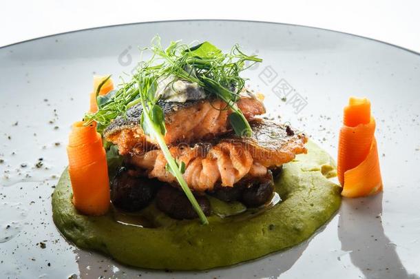 特写镜头烘烤制作的鲑鱼肉片起初装饰和绿叶蔬菜
