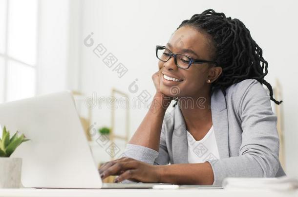 欢乐的非洲式发型办公室女孩使用便携式电脑在工作场所