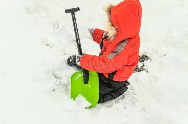 小的男孩演奏和一雪铲子采用一桩关于雪