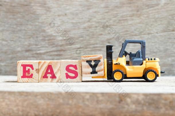 玩具铲车拿住块英语字母表的第25个字母采用单词eas英语字母表的第25个字母向木材背景