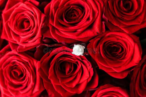 美丽的白色的金<strong>珍珠</strong>戒指和花束关于红色的<strong>玫瑰</strong>,奢侈