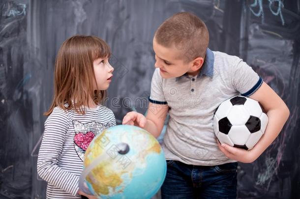 男孩和小的女孩使用球关于地球采用前面关于黑板