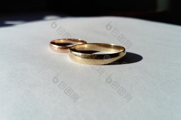 金珠宝,两个金色的婚礼戒指向一白色的b一ckground
