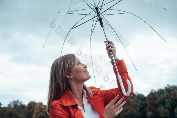 高加索人女孩和红色的一种斜纹防水布料和<strong>透明</strong>的<strong>雨伞</strong>锡蒂