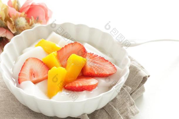 一半的将切开草莓和芒果向酸奶和茶水