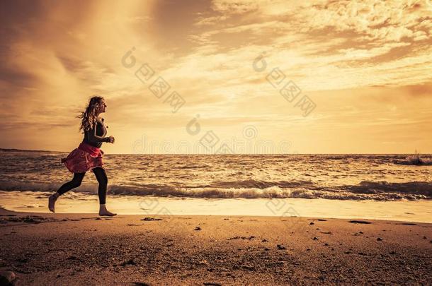 女人做海滩跑向指已提到的人海滩在日落