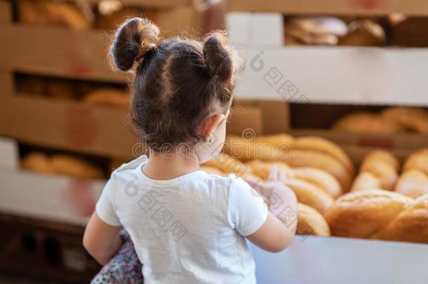 背看法小的女孩,在期间挑选新鲜的面包一条面包采用面包房