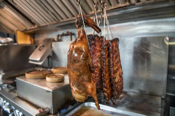 煮熟的北京烤鸭子和熏制的肋骨向饭店厨房.