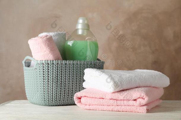 篮和干净的毛巾和洗衣店液体向木制的背景