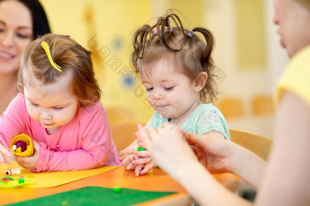 孩子们演奏和塑像用黏土在幼儿园或幼儿游戏组