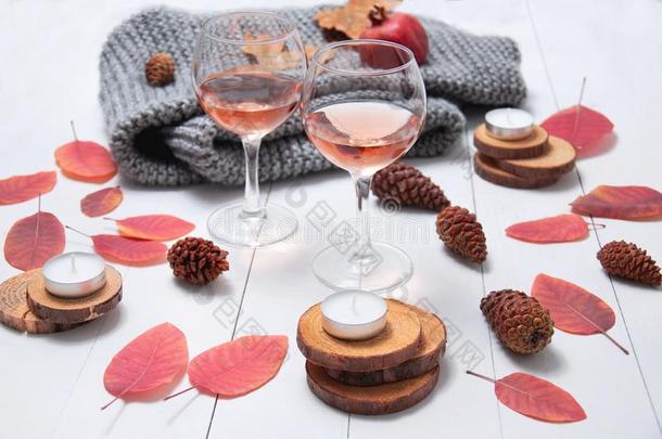 小的蜡烛,两个眼镜和玫瑰葡萄酒,圆锥细胞,干的干燥的红色的树叶
