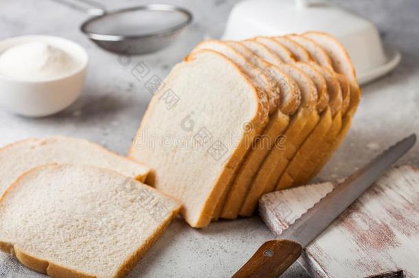 将切开关于新鲜的一条面包关于白色的面包和面粉和黄油向光