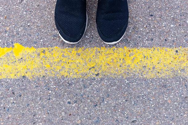 旅游鞋向沥青路和黄色的线条路标记,顶看法