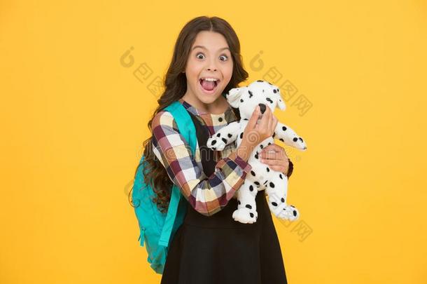 不由得想搂抱的朋友.幸福的小的小孩拿住玩具狗黄色的背景