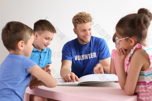 年幼的志愿者阅读书和孩子们在表
