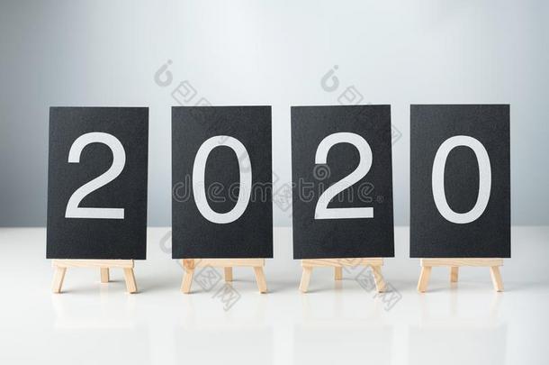 幸福的新的年2020和黑板向白色的表和灰色的背