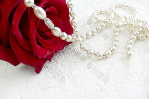 红色的玫瑰和珍珠向白色的织地粗糙的背景.
