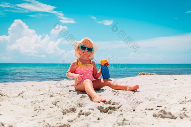 太阳保护-小的女孩和防晒霜在海滩
