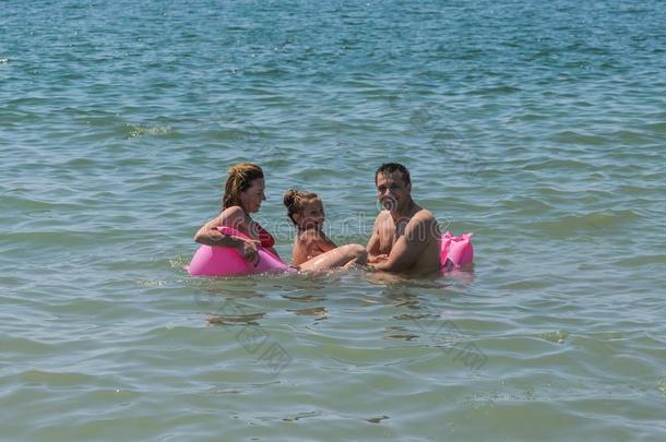 幸福的家庭妈妈,爸爸和女儿比赛向一天空床垫游泳